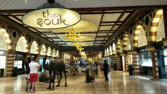 Interior de centro comercial com estátuas de camelos, letreiro The Souk