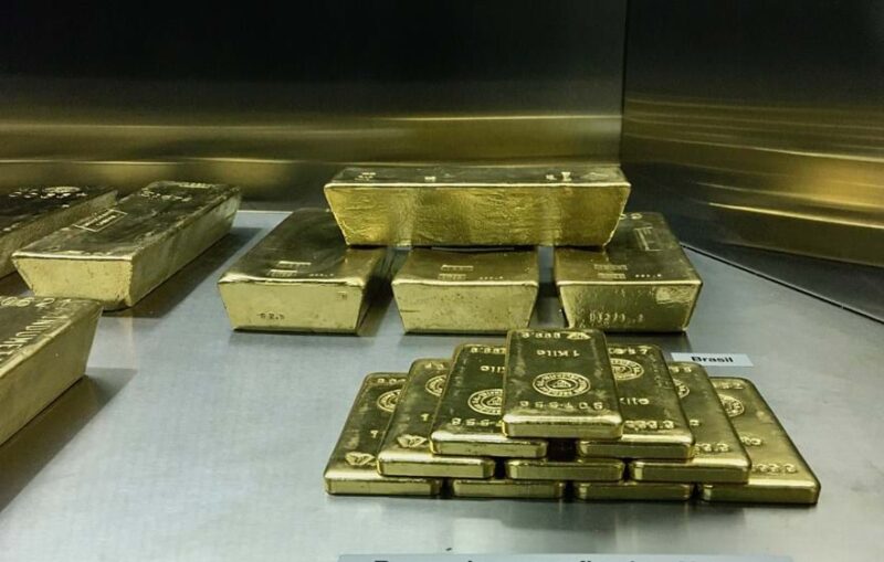 Barras de ouro empilhadas num cofre, com etiqueta Brasil