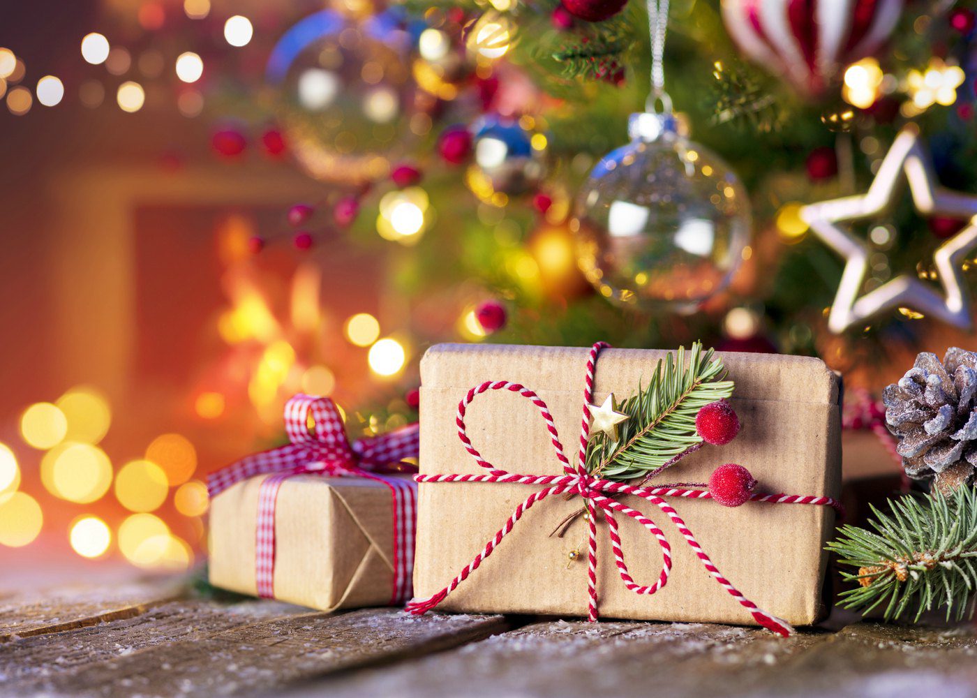 Presentes de Natal embrulhados junto à árvore, com laços e pinhas